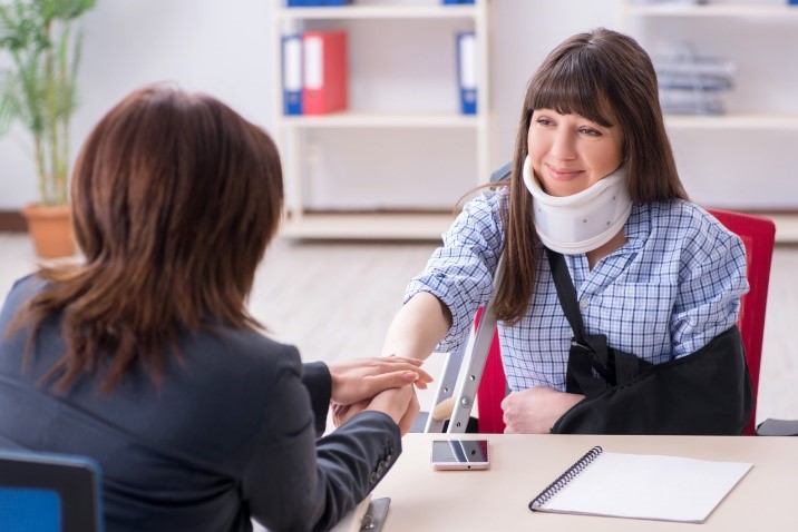 woman in neck brace speaking with lawyer